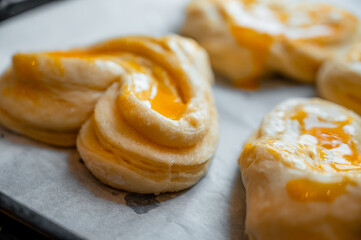 Close-up of a cook brushing egg yolk on raw buns before baking to achieve a shiny golden crust.