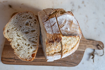 Bread, traditional sourdough, homemade sourdough bread cut into slices on a rustic wooden cutting board, and linen cloth. Healthy organic food. Concept of traditional leavened bread baking methods. 