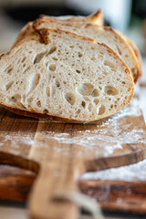Bread, traditional sourdough, homemade sourdough bread cut into slices on a rustic wooden cutting board, and linen cloth. Healthy organic food. Concept of traditional leavened bread baking methods. 