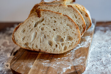Bread, traditional sourdough, homemade sourdough bread cut into slices on a rustic wooden cutting board, and linen cloth. Healthy organic food. Concept of traditional leavened bread baking methods. 
