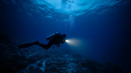 Deep sea diver exploring underwater with a flashlight. The beam cuts through the dark blue water, illuminating the ocean floor and life. Adventure awaits in the depths.