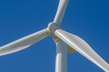 Close-up view of a wind turbine against a clear blue sky.
