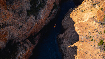 Panoramic aerial view of a cove between Esterel Mountains red cliffs with a board on the water, Mediterranean Sea, French Riviera, Southern France, scenic coastline, turquoise water