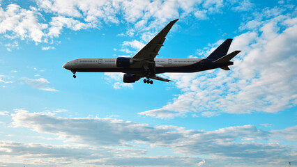 Airplane flying preparing for landing against a blue sky with clouds, travel and aviation