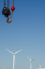 Crane hook over wind turbines, symbolizing renewable energy progress