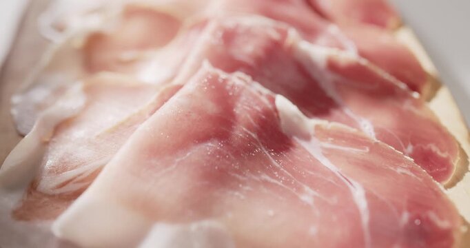 Sliding closeup over sliced ham on a cutting board. Cold meat close up food background.