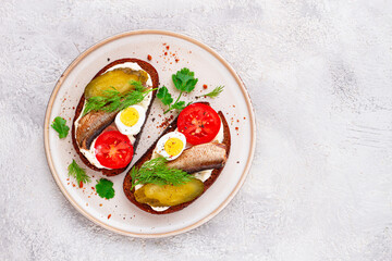 sandwiches on rye bread, with sprats, quail eggs, fresh tomatoes and pickled cucumber, appetizer, breakfast, homemade,