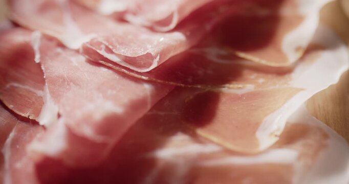 Sliding closeup over sliced ham on a cutting board. Cold meat close up food background.
