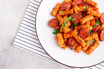 rigatoni pasta with spicy sausage, and rich tomato sauce served, on a white plate, homemade,