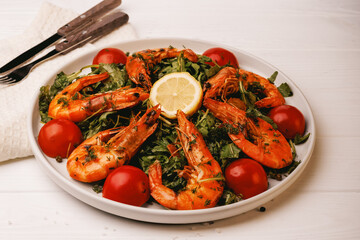 salad in a plate with king prawns and greens with tomatoes and lemon