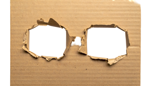Close-up of brown cardboard with two irregularly shaped, black holes resembling eyes - Powered by Adobe