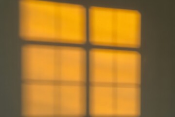 Warm Golden Window Shadow Cast on Neutral Wall Creating a Cozy Geometric Light Pattern in Soft Indoor Setting
