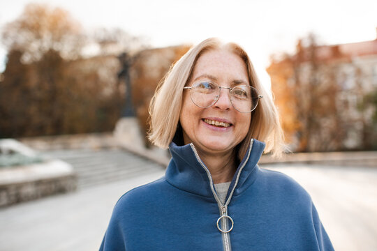 Smiling senior woman 55-60 year old wearing glasses outdoors. Stylish middle age female.