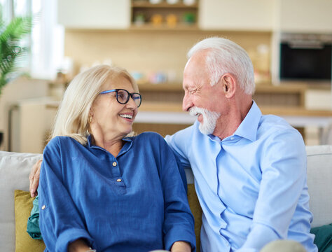 Portrait of a happy senior couple embracing talking at home - Powered by Adobe