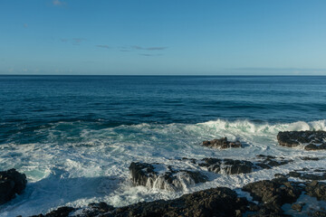 Scenic vista of waves breaking against the rocky shore along the Kaena Point trail on Oahu, Hawaii