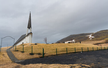 Stunning church on a hillside in Iceland with dramatic cloudy sky and surrounding barren landscape