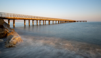 Sunrise view over a tranquil pier stretching into the calm sea during early morning. Limni Pier Cyprus
