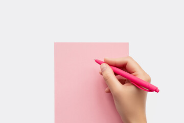 Hand writing on a pink paper with a pink pen top view