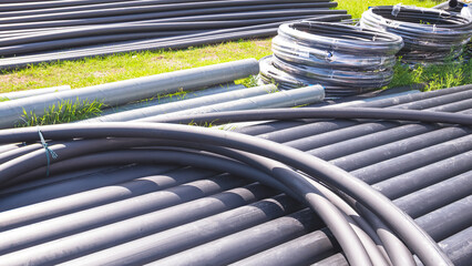 Group of black HDPE pipes on the ground in construction site for underground water piping installation work.