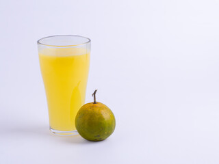 Fresh glass of orange juice with whole unpeeled orange on white background. Isolated citrus drink with copy space, healthy natural beverage concept for food, nutrition, and freshness.
