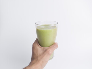 Hand holding a tall glass of fresh green avocado smoothie/juice on white. Highlights healthy lifestyle, vegan diet, detox, summer refreshment, and organic fruit drink.
