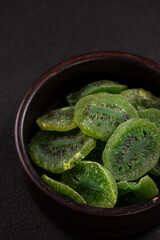 Dried kiwi slices filling a dark ceramic bowl