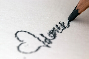 Fototapeta premium Scribbling with a pencil on white paper. Close-up. heart shape