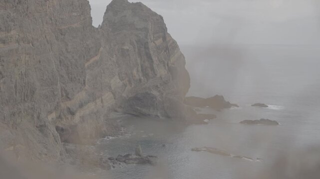 Medium shot of volcanic cliff face and dark rock formations along coast in Madeira Portugal (SLOG3)