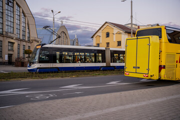 Riga city tram passing yellow bus near Central Market pavilions showing contrast of public transport systems, modern mobility and everyday rhythm in historical urban environment