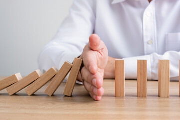 Businessman hand stop falling down of wood block. planning and strategy business disruption concept