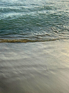 Calm river waves on sandy beach.