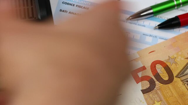   Italian taxes. The IRPEF tax return with pen and calculator. Tax calculation. Euro banknotes. Financial concept. Settlements in Italy
