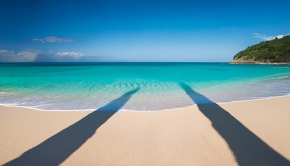 Fototapeta premium Two Long Shadows On A Sandy Beach With Blue Sky And Turquoise Water