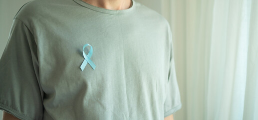 Close up of a man wearing a blue satin ribbon on his chest. Symbol of prostate cancer awareness,...