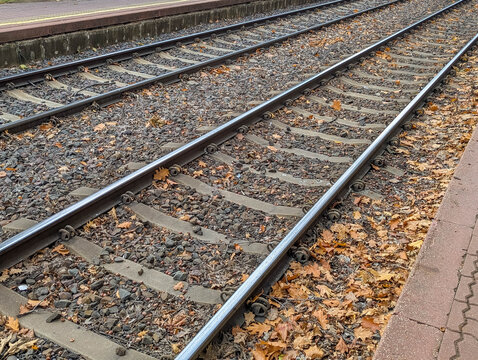 Warsaw, Poland, October 20, 2025. Railway tracks with autumn leaves on wooden sleepers at Warszawska Kolej Dojazdowa WKD station Warsaw Poland. High quality photograph