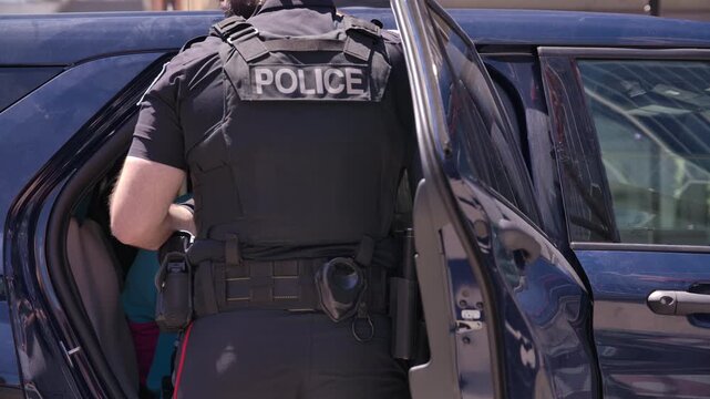 police officer with suspect in back of police car