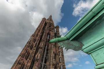 Ancient and impressive view of Strasbourg Cathedral with famous iron gargoyle in foreground under cloudy sky