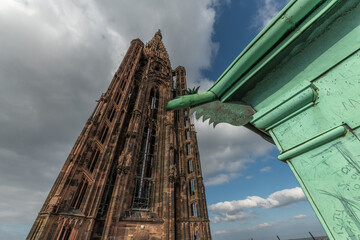 Ancient and impressive view of Strasbourg Cathedral with famous iron gargoyle in foreground under cloudy sky