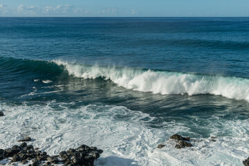 Scenic vista of waves breaking against the rocky shore along the Kaena Point trail on Oahu, Hawaii