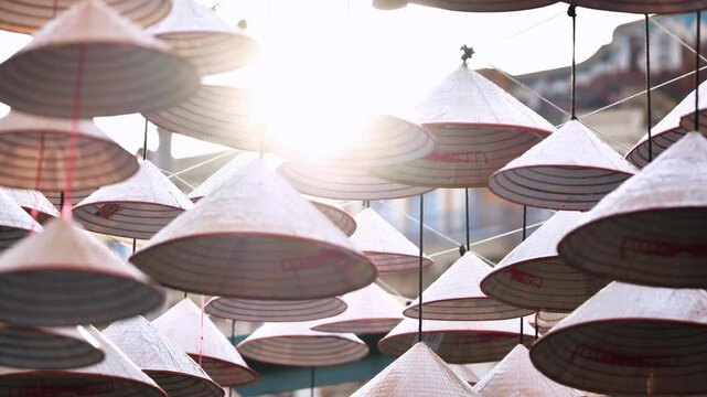 Traditional conical hats hanging in a market in Vietnam, creating beautiful patterns with sunlight shining through