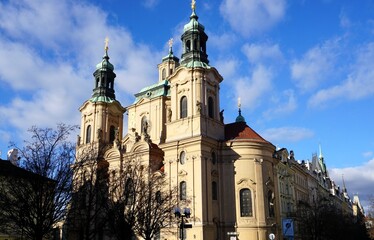 Side view of the ornate Gothic facade and landmark towers of St. Nicholas Church (Stare Mesto) in the Old Town of Prague, Czech Republic, on a sunny day