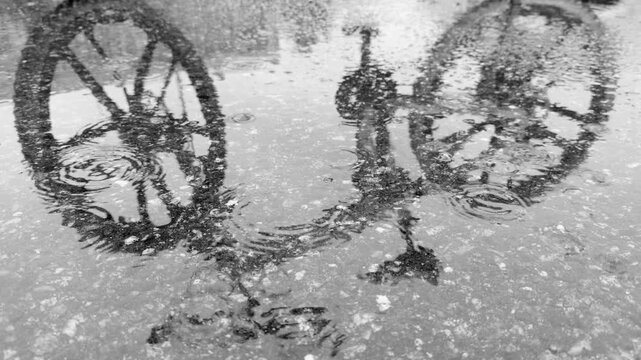 Seamless loop bicycle reflected in a puddle on a rainy day, creating a serene and artistic black and white image