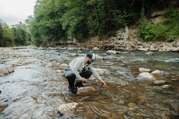 Obraz premium Fisherman releasing trout in pristine river after successful catch