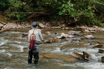 Fisherman catching trout in wild river