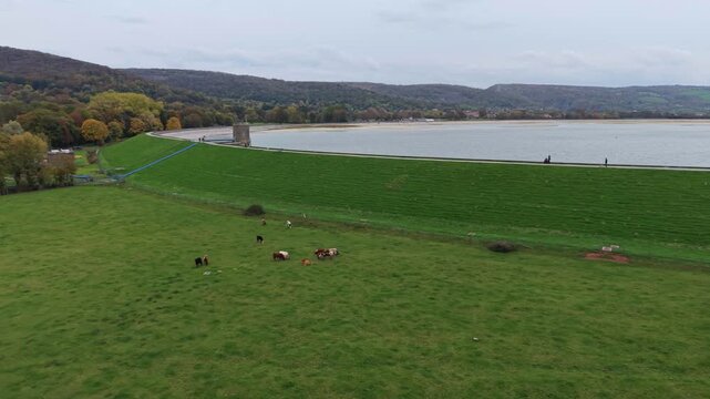 Aerial drone footage showcasing Chedar Reservoir and the surrounding countryside in Somerset, UK. The video captures calm water, rolling hills, farmland, and lush greenery from an elevated perspective