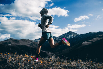 Trail runner running on the high altitude grassland mountain top trail