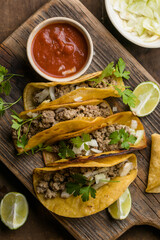 Birria tacos with dipping sauce on wooden board