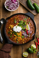 Chili con carne on wooden table with corn and spices