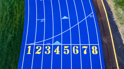 Aerial image of a new blue and yellow eight, 8, lane running track with white lane lines and other markings.	