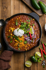 Chili con carne on wooden table with corn and spices